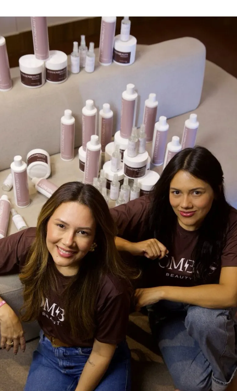 Camila Luz e Caroline Luz sorrindo ao lado dos produtos da marca própria Combos